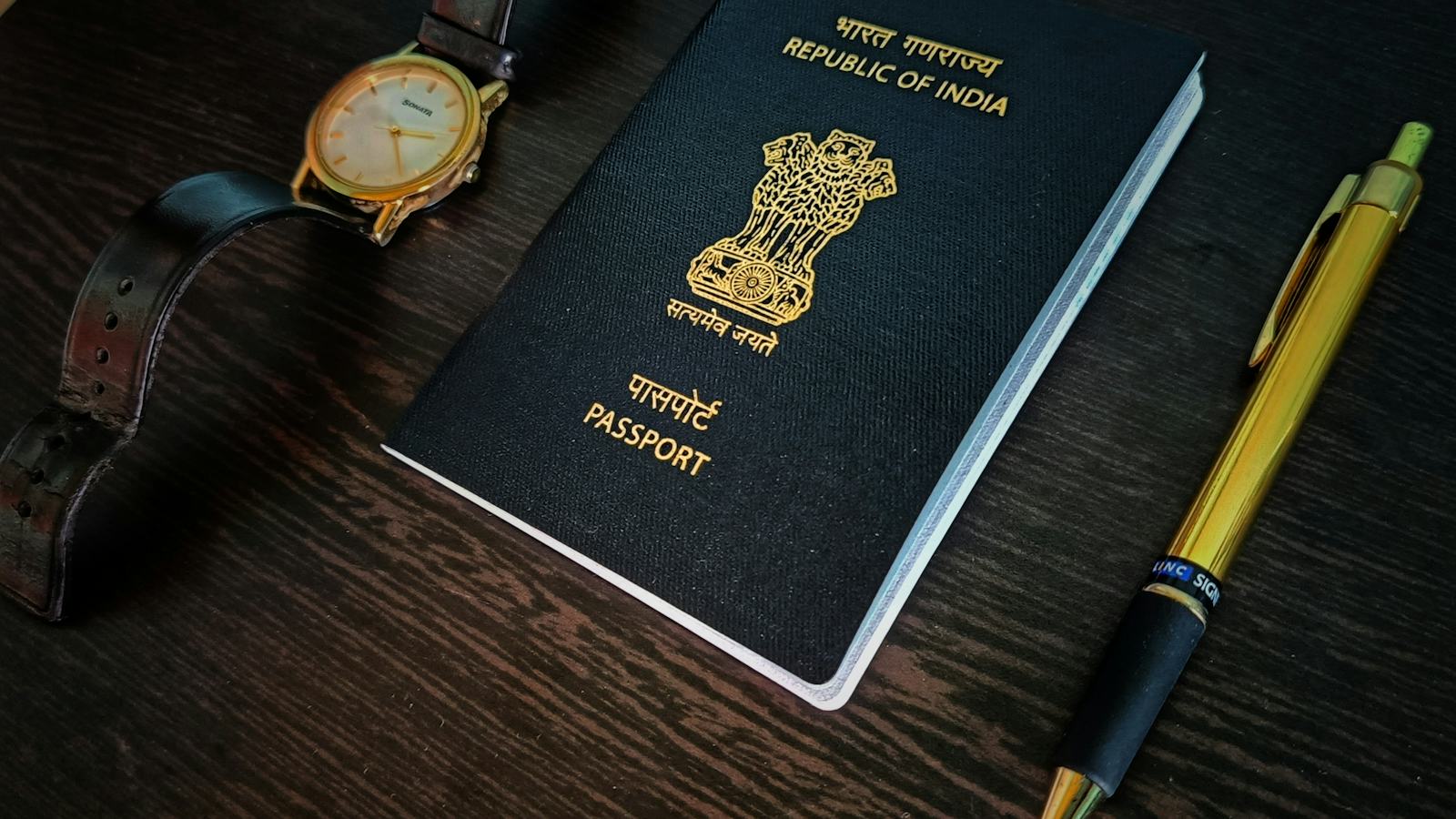A passport, a watch and a pen laid out on a table