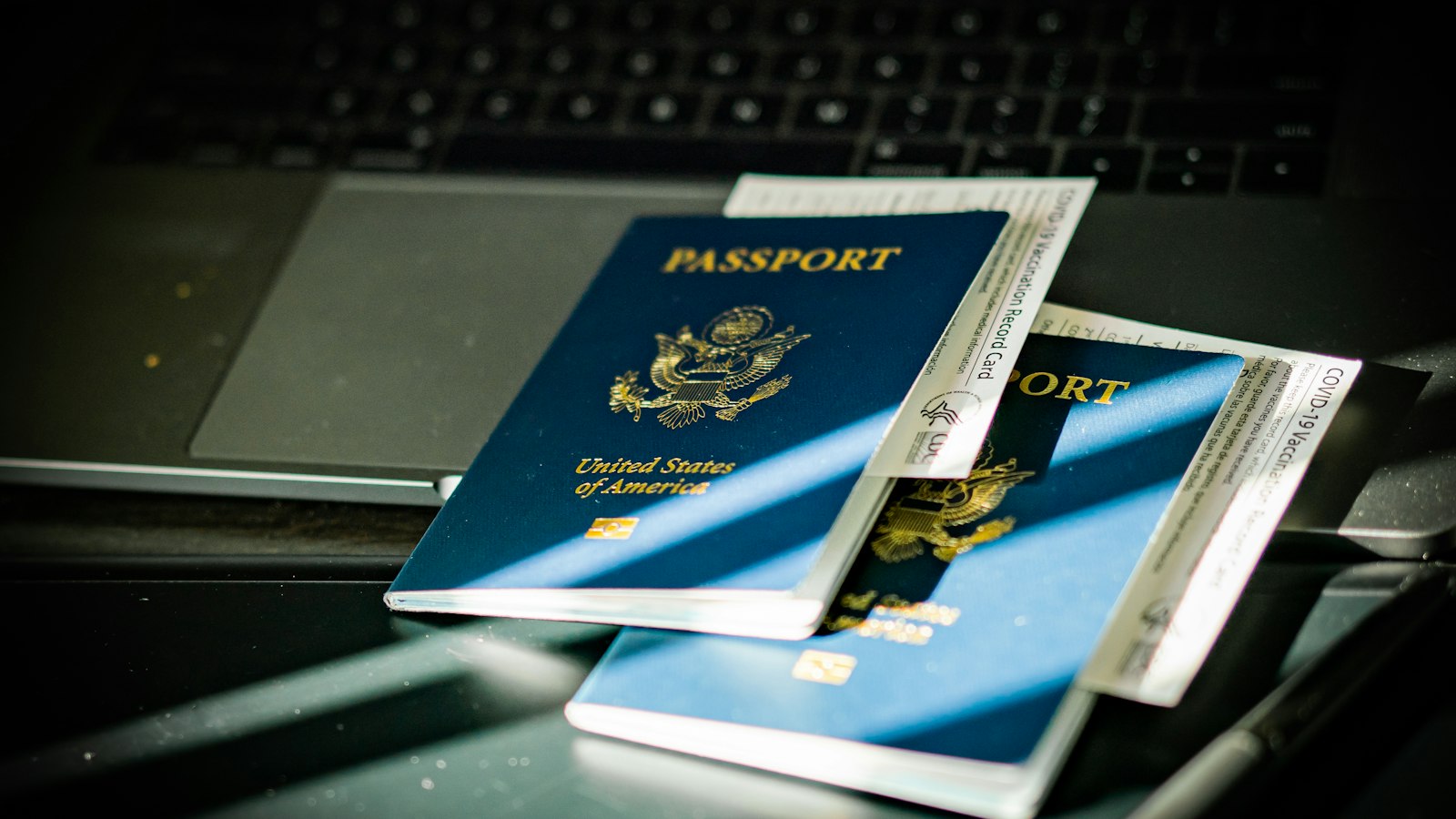 Two US passports and travel documents resting on a laptop keyboard