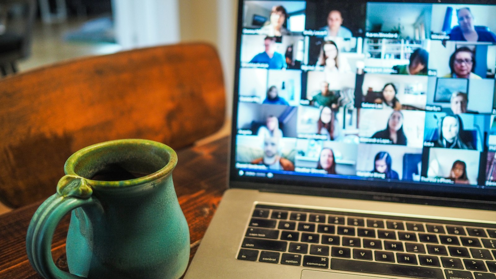 A laptop screen showing a video call, with a cup of coffee beside it