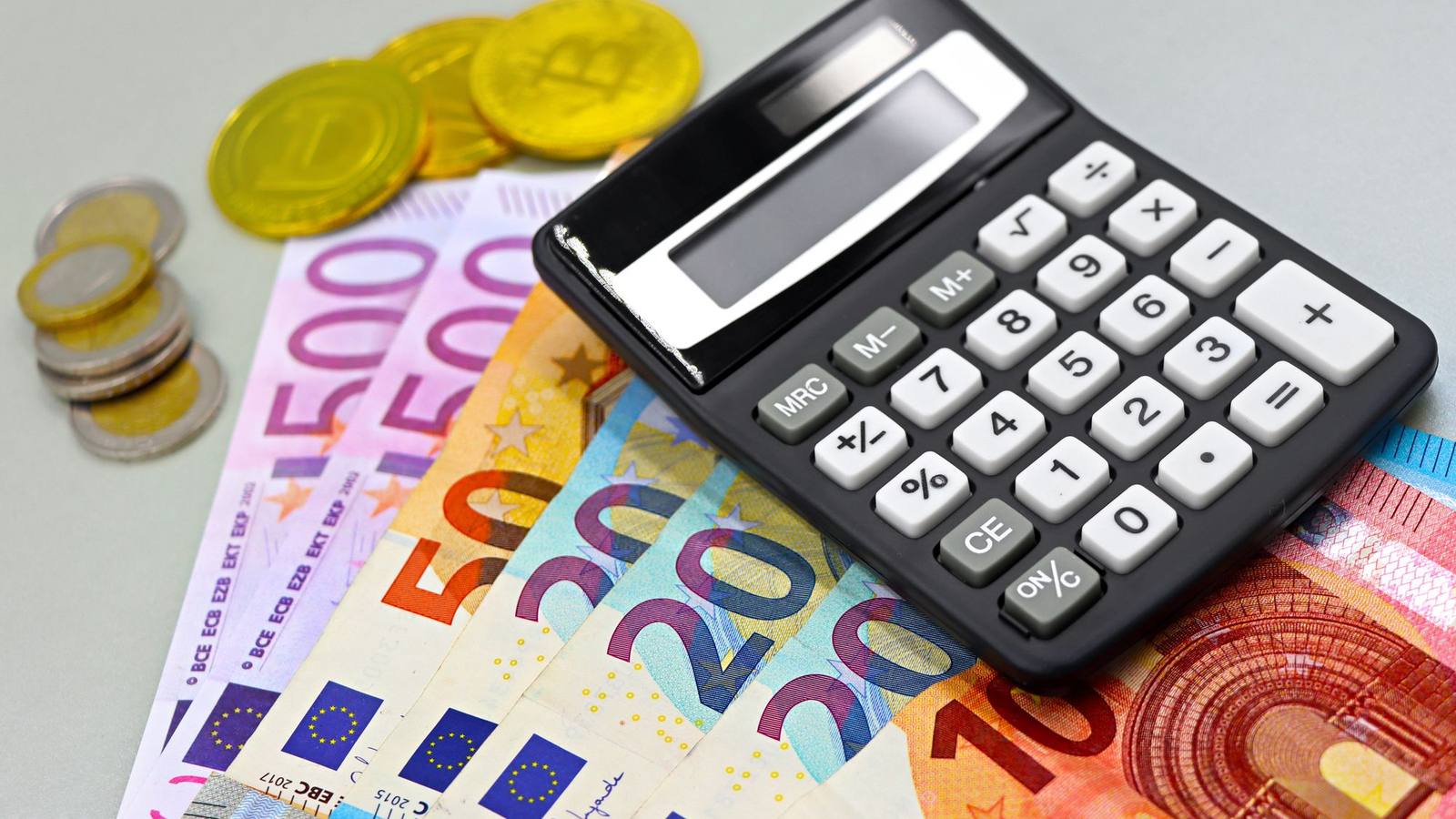Euro banknotes and coins next to a calculator.